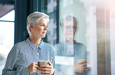 Buy stock photo Shot of an attractive mature businesswoman drinking coffee while looking out of her office window
