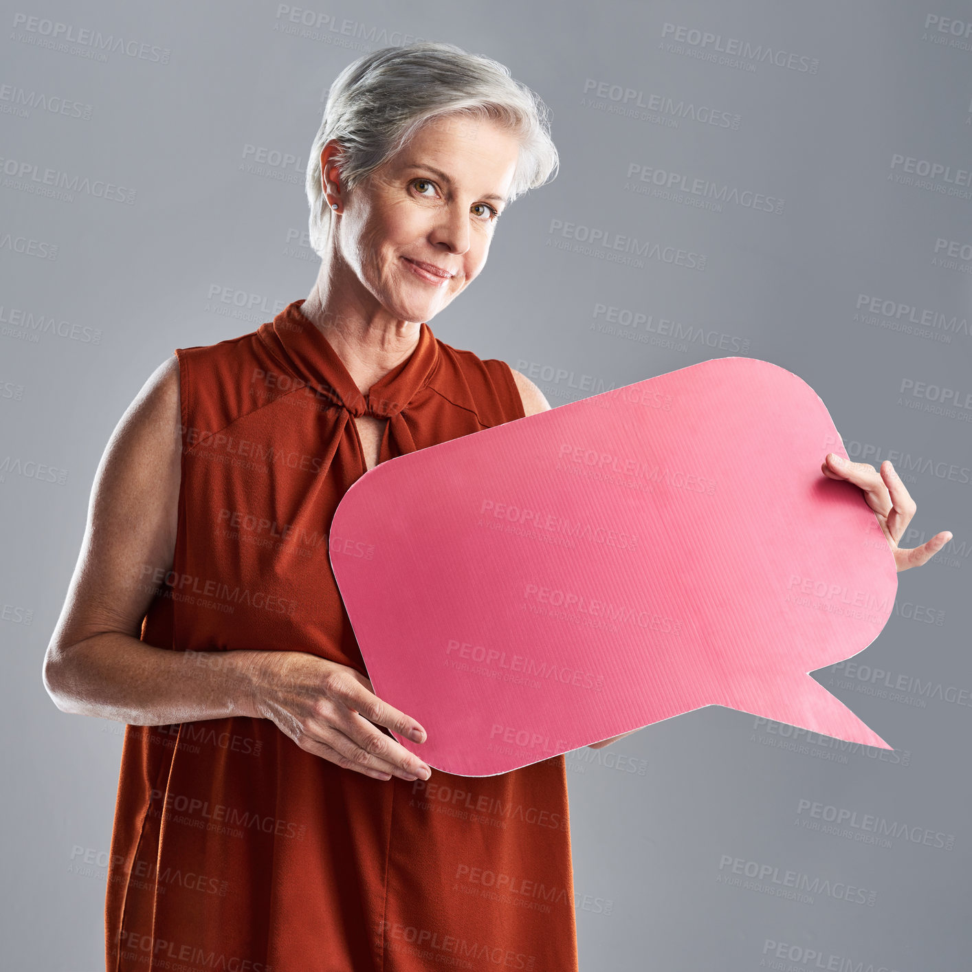 Buy stock photo Portrait of a mature woman holding a speech bubble against a grey background