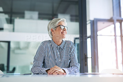 Buy stock photo Shot of an attractive mature businesswoman looking out of a window while sitting at her office desk at work