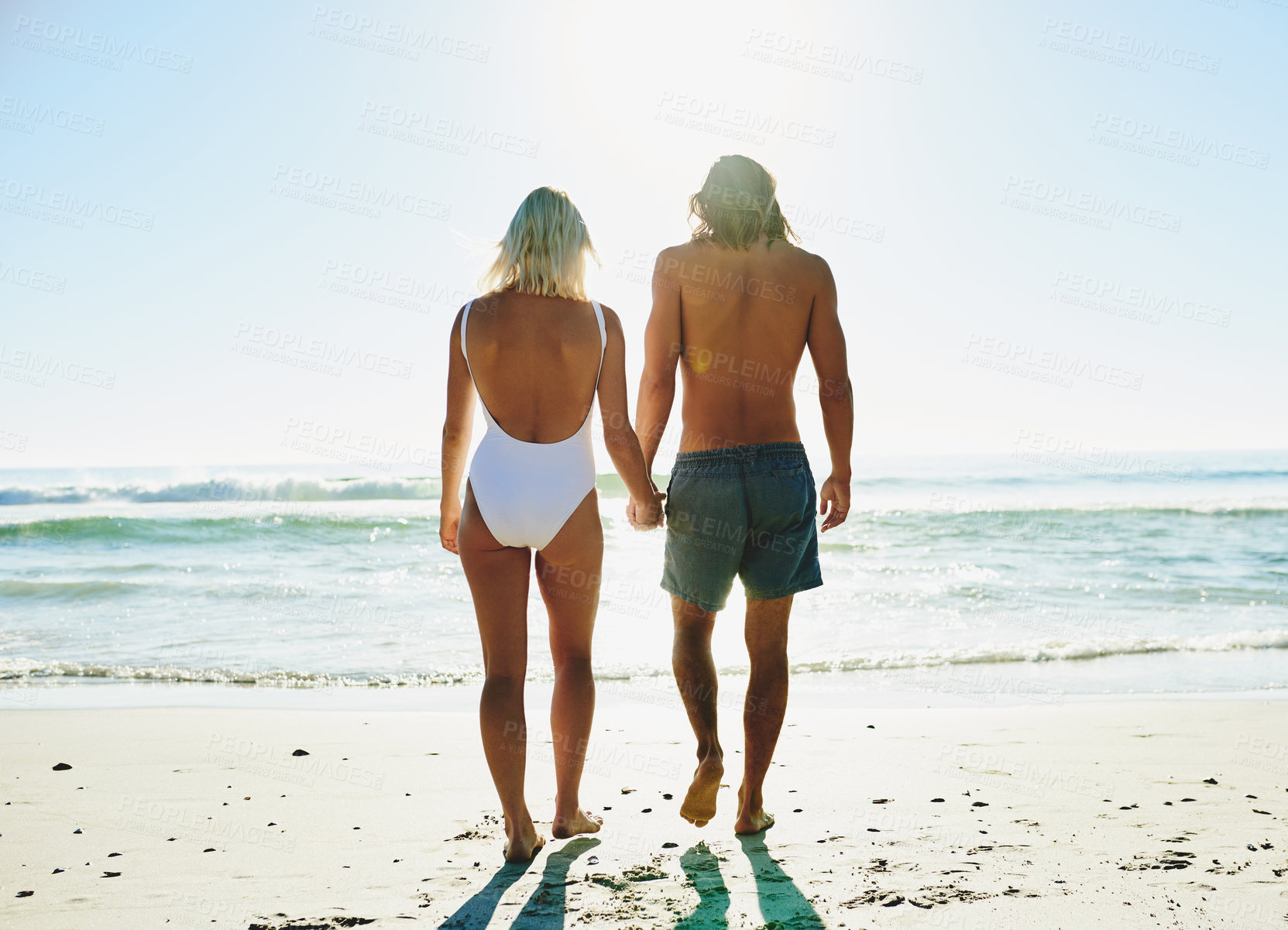 Buy stock photo Rearview shot of a young couple enjoying some quality time together at the beach