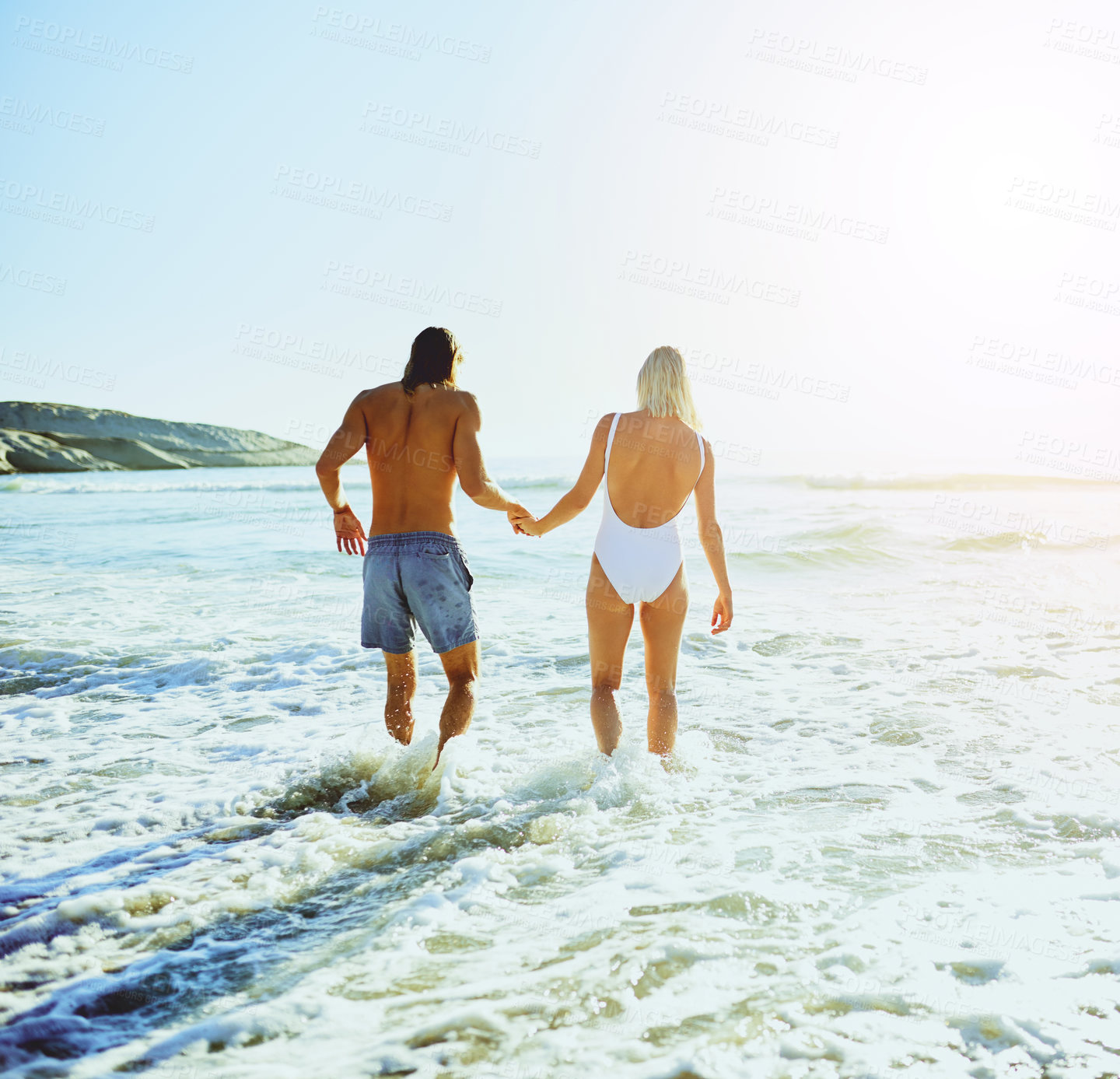 Buy stock photo Rearview shot of a young couple enjoying some quality time together at the beach