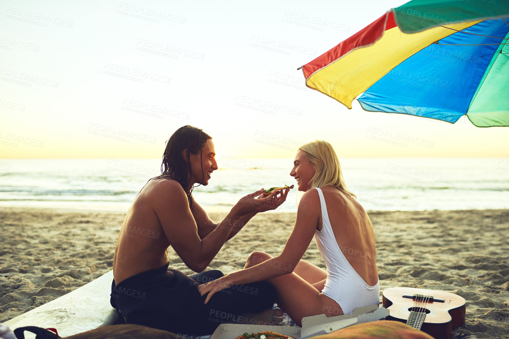 Buy stock photo Couple, happy and picnic on beach for love, support and milestone in relationship at sunset. Man, woman or sharing food at ocean for bonding, summer vacation or eating in evening on sand in Australia