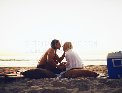 Buy stock photo Shot of a young affectionate couple sharing a tender moment during a date on the beach at sunset