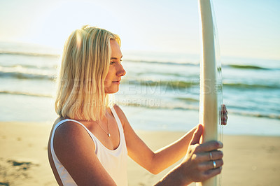 Buy stock photo Cropped shot of an attractive young woman standing in a swimsuit holding a surfboard on the beach