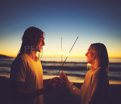 Buy stock photo Night, couple and playing with sparklers, beach and celebration for New Year, smile and bonding. Outdoor, man and woman at sea, sunset and fun for people, relationship and scenery in holiday and love