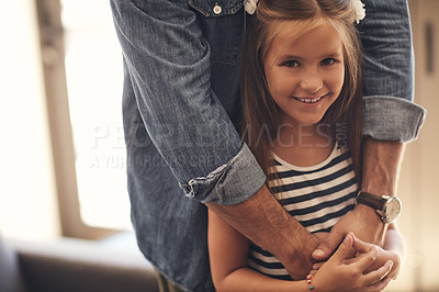 Buy stock photo Portrait of an adorable little girl standing with her father’s arms around her at home