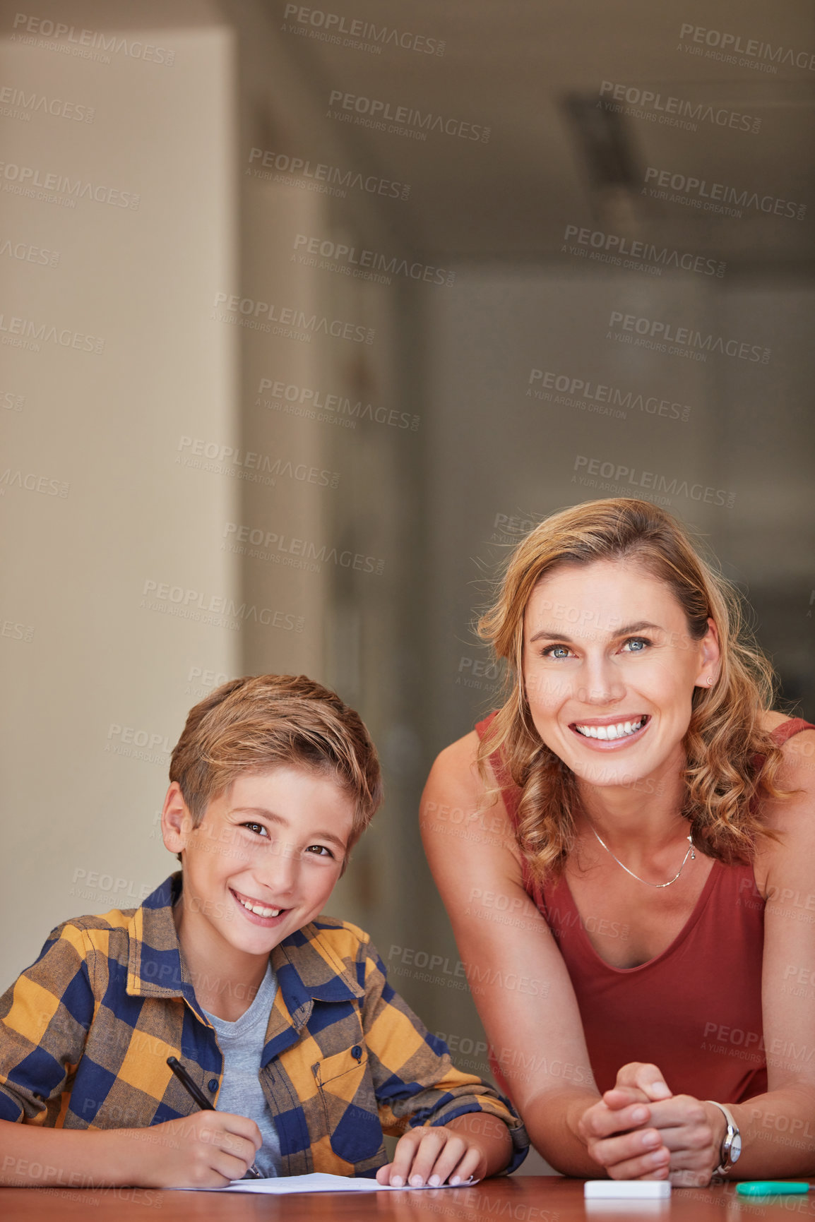 Buy stock photo Shot of a young woman helping her son with his homework at home