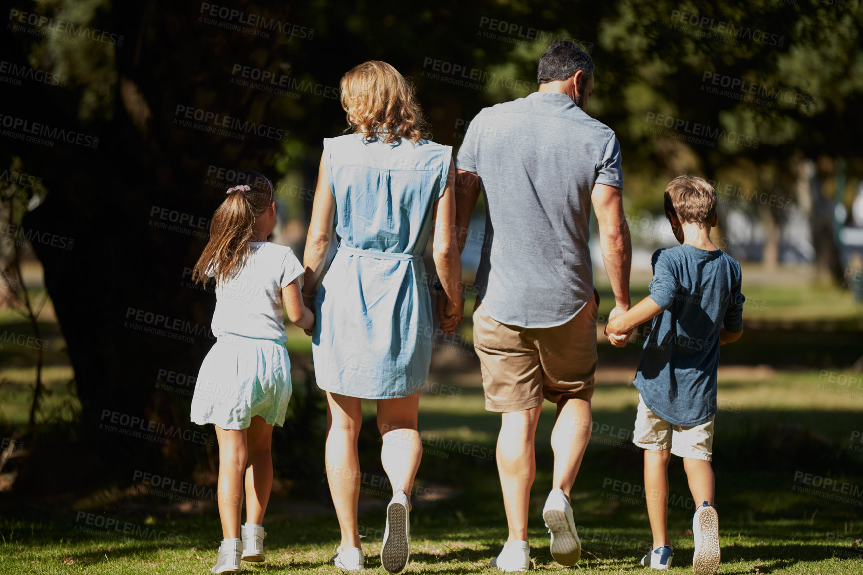 Buy stock photo Rearview shot of a happy young family going for a walk in the park