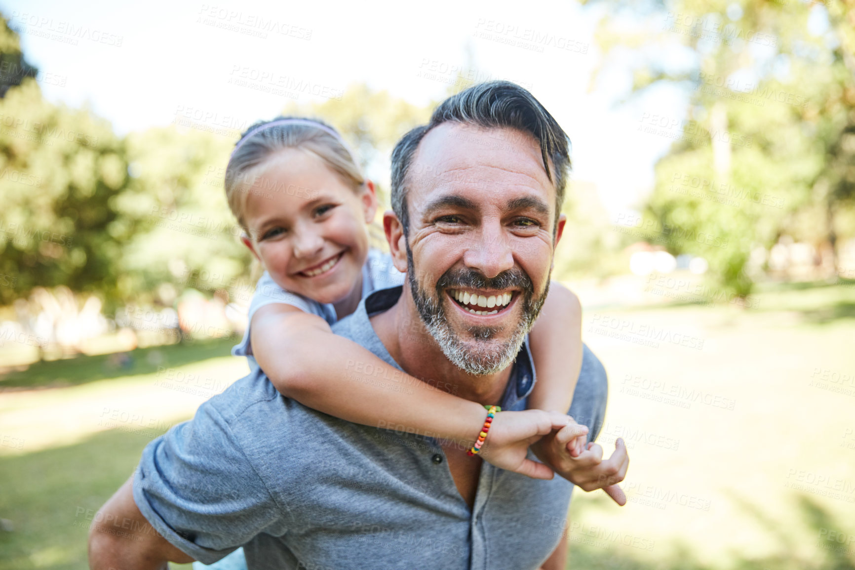 Buy stock photo Shot of an adorable little girl enjoying a piggyback ride with her father in the park