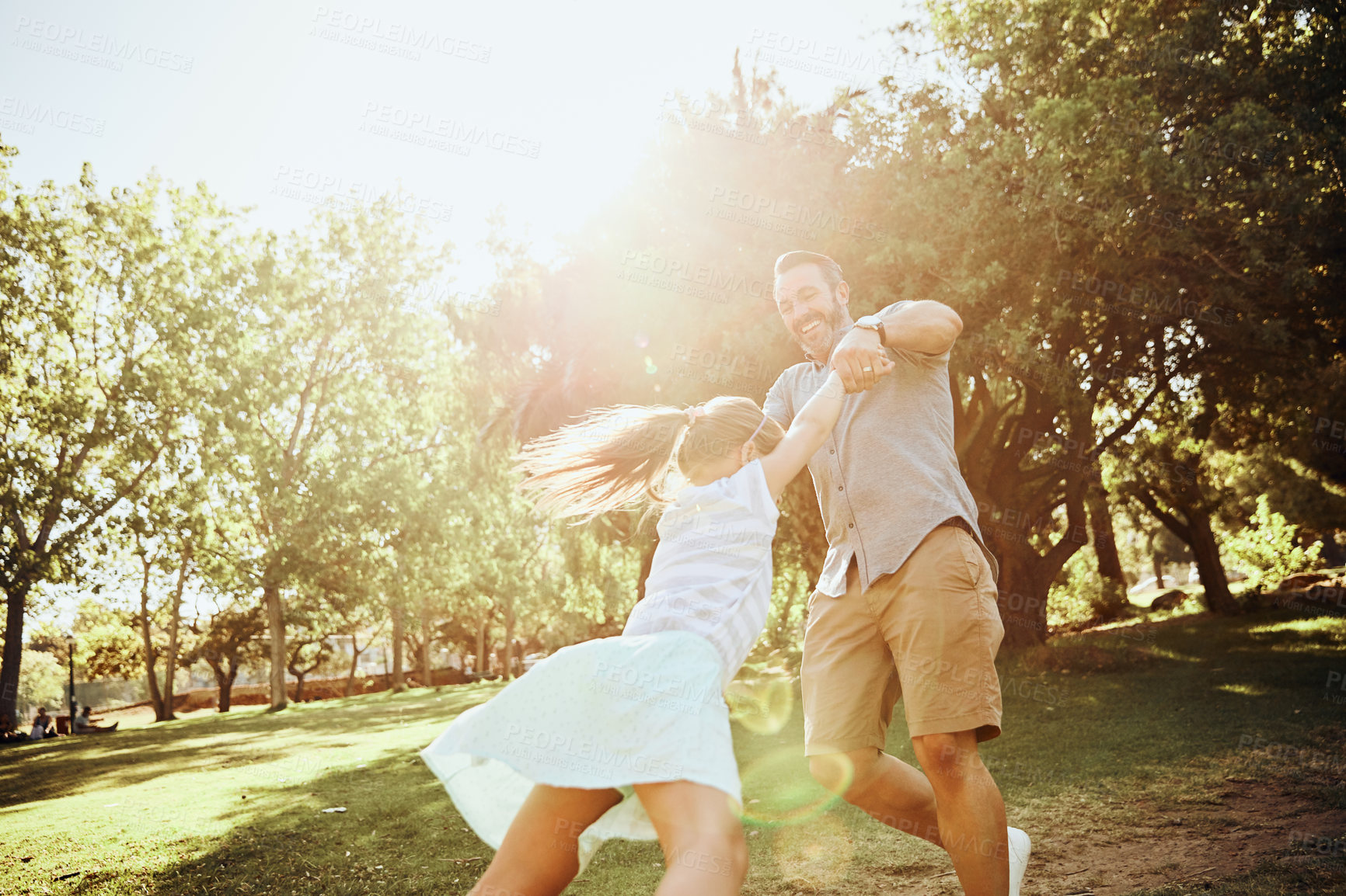 Buy stock photo Shot of an adorable little girl being swung around by her father in the park