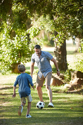 Buy stock photo Shot of an adorable little boy playing soccer with his father in the park