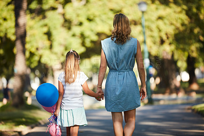 Buy stock photo Rearview shot of a little girl holding balloons and walking in the park with her mother