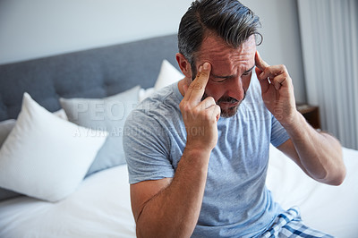 Buy stock photo Cropped shot of an attractive mature man suffering from a headache in his bedroom in the morning