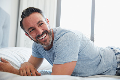 Buy stock photo Cropped shot of an attractive mature man looking happy while lying on a bed at home in the morning