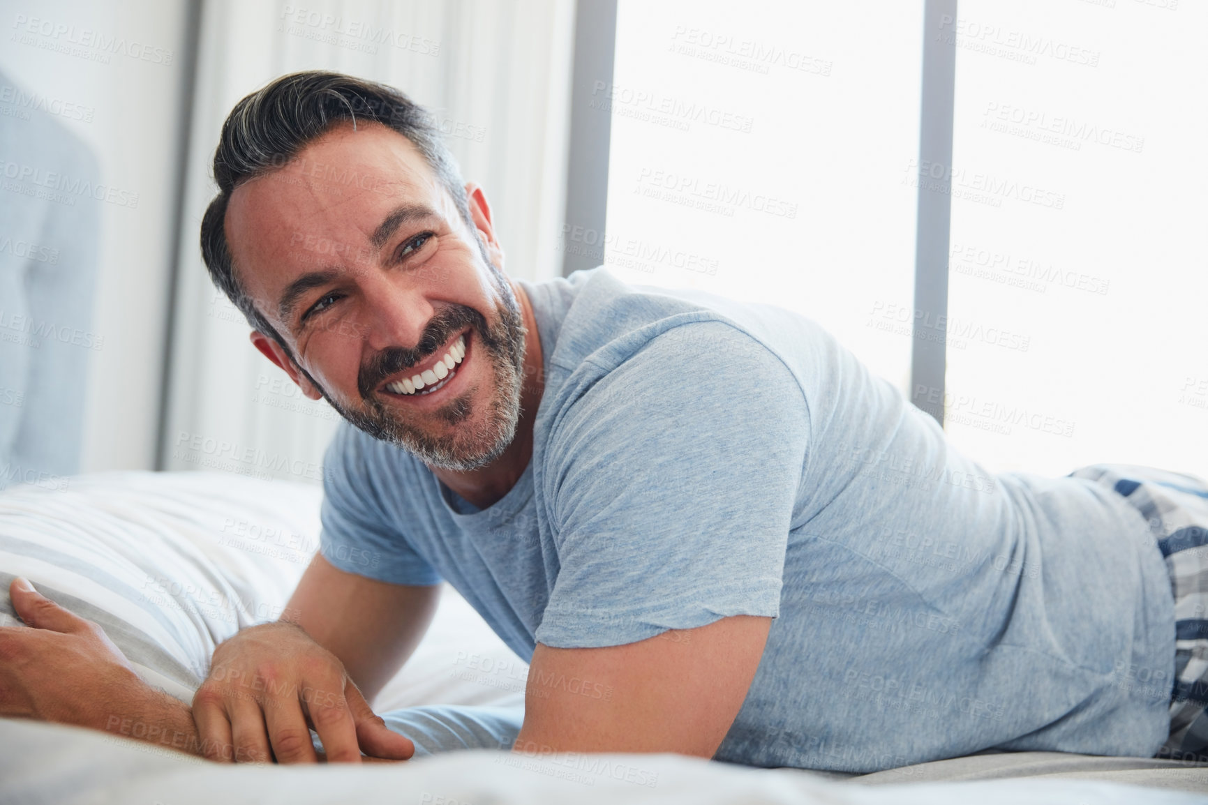 Buy stock photo Cropped shot of an attractive mature man looking happy while lying on a bed at home in the morning