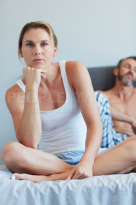 Buy stock photo Cropped portrait of an attractive young woman looking thoughtful in the bedroom with her husband in the background