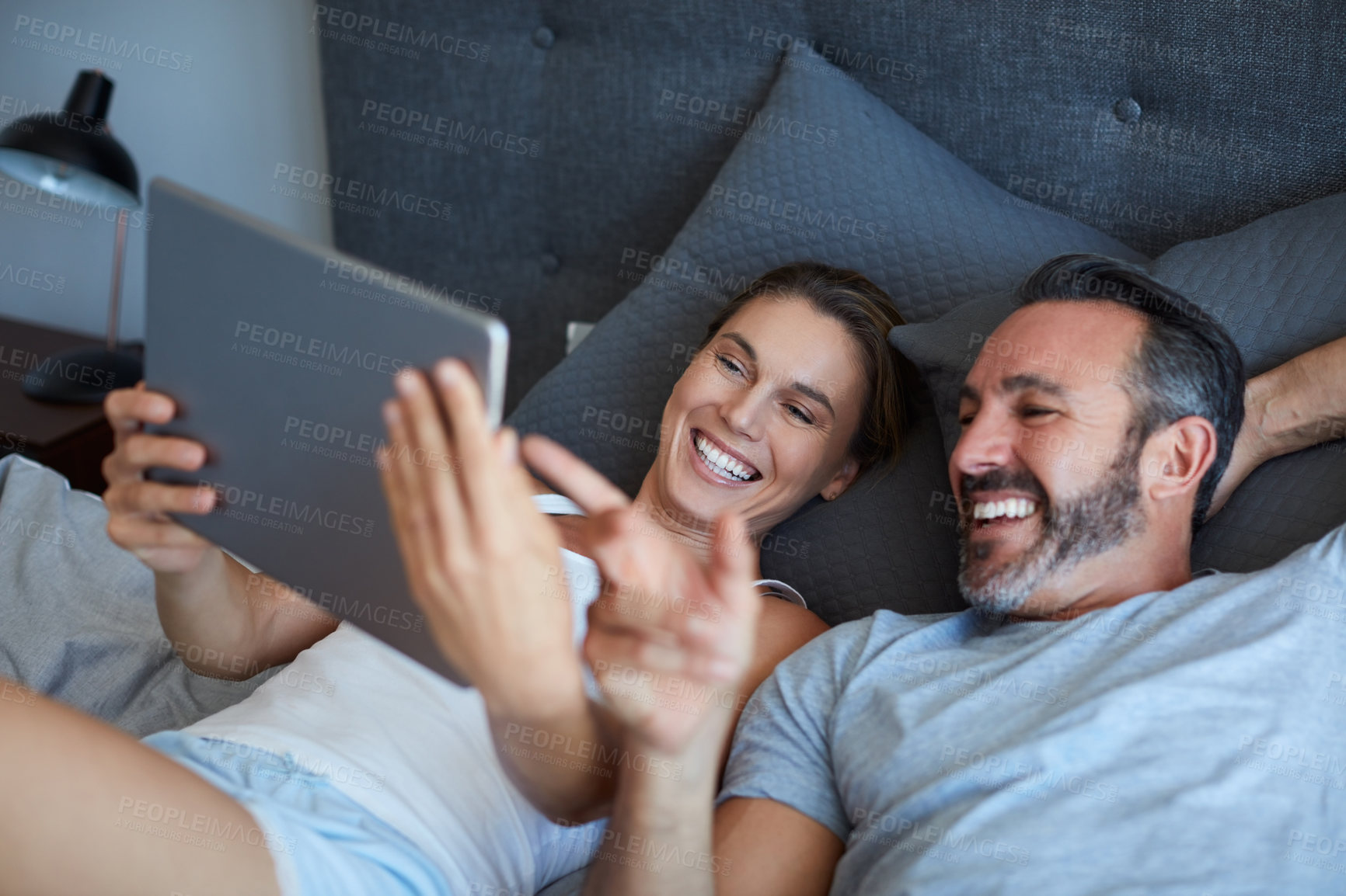 Buy stock photo Smile, reading or couple with tablet on bed, funny social media post or streaming movie for cozy morning. Laugh, watch video or people in home with tech for subscription app, comedy film or bonding