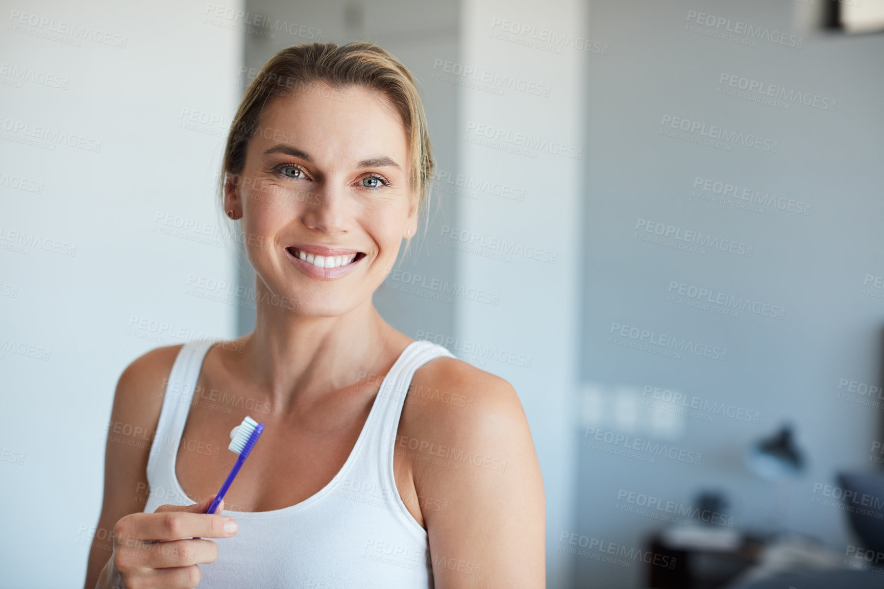 Buy stock photo Cropped portrait of an attractive young woman holding a toothbrush at home