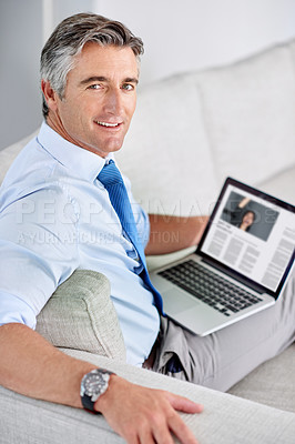 Buy stock photo Portrait of a confident mature businessman and sitting on a sofa while working on his laptop indoors