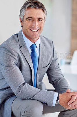 Buy stock photo Portrait of a confident mature businessman wearing a suit and sitting on a sofa with his hands clasped