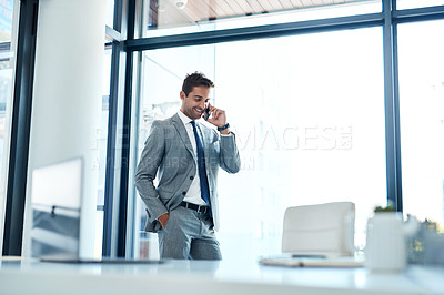 Buy stock photo Shot of a businessman talking on his cellphone while standing in his office