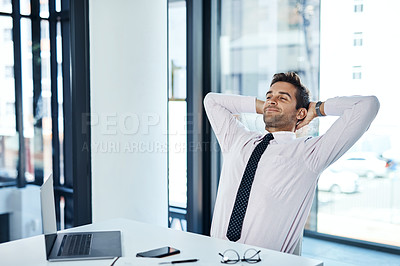 Buy stock photo Shot of a businessman looking relaxed while sitting at his desk