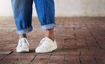 Buy stock photo Cropped shot of an unrecognizable person standing on a brick floor while wearing white sneakers and blue jeans
