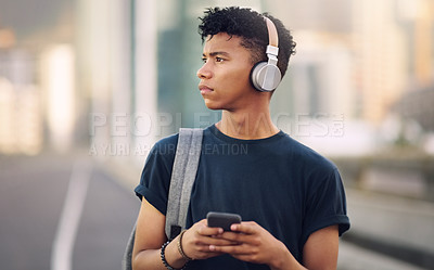 Buy stock photo Cropped shot of a handsome young man waking down the street and listening to music off his cellphone