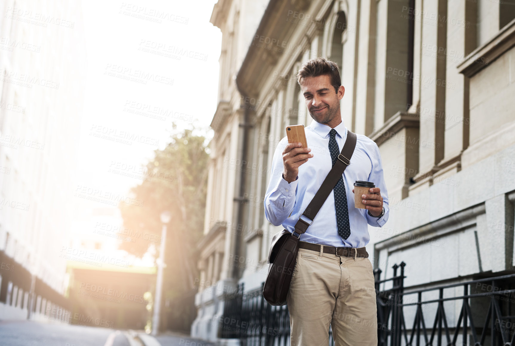 Buy stock photo Shot of a handsome young businessman texting on his cellphone while heading to work in the morning