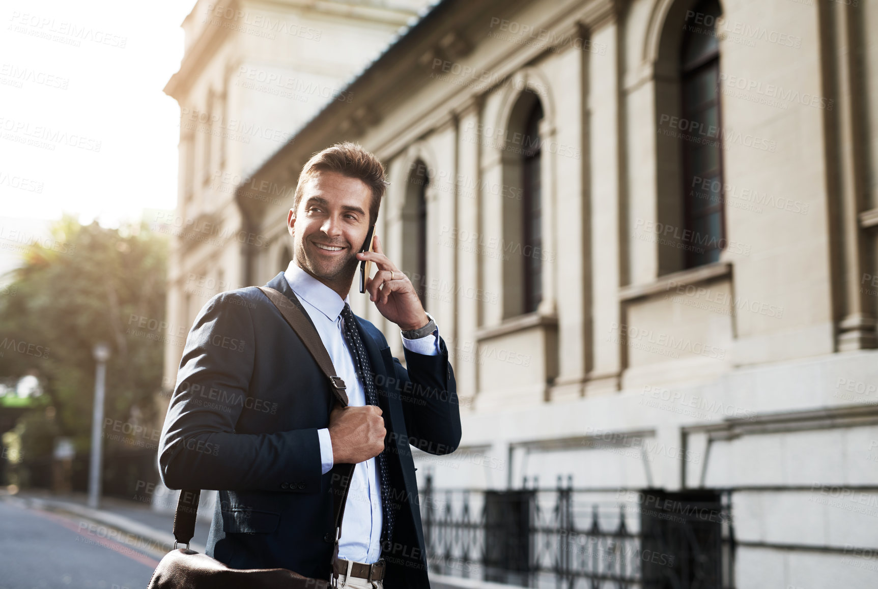Buy stock photo Shot of a handsome young businessman talking on his cellphone while heading to work in the morning