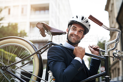 Buy stock photo Shot of a handsome young businessman carrying his bicycle while making his way to work in the morning