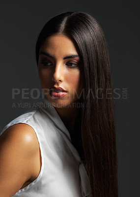 Buy stock photo Studio shot of an attractive young woman wearing a white blouse and posing against a dark background