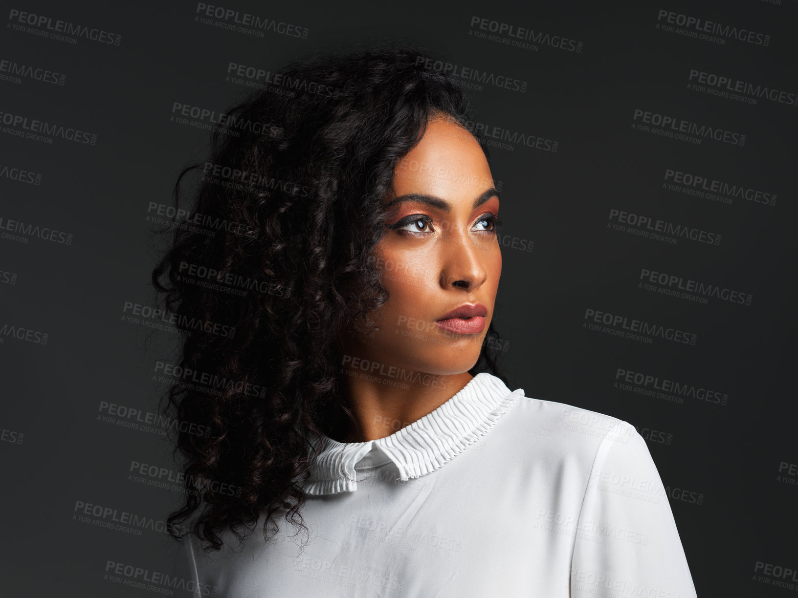 Buy stock photo Studio shot of an attractive young woman wearing a white blouse and posing alone against a dark background