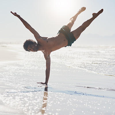 Buy stock photo Full length shot of a handsome young man balancing on his hand while dancing on the beach during the day
