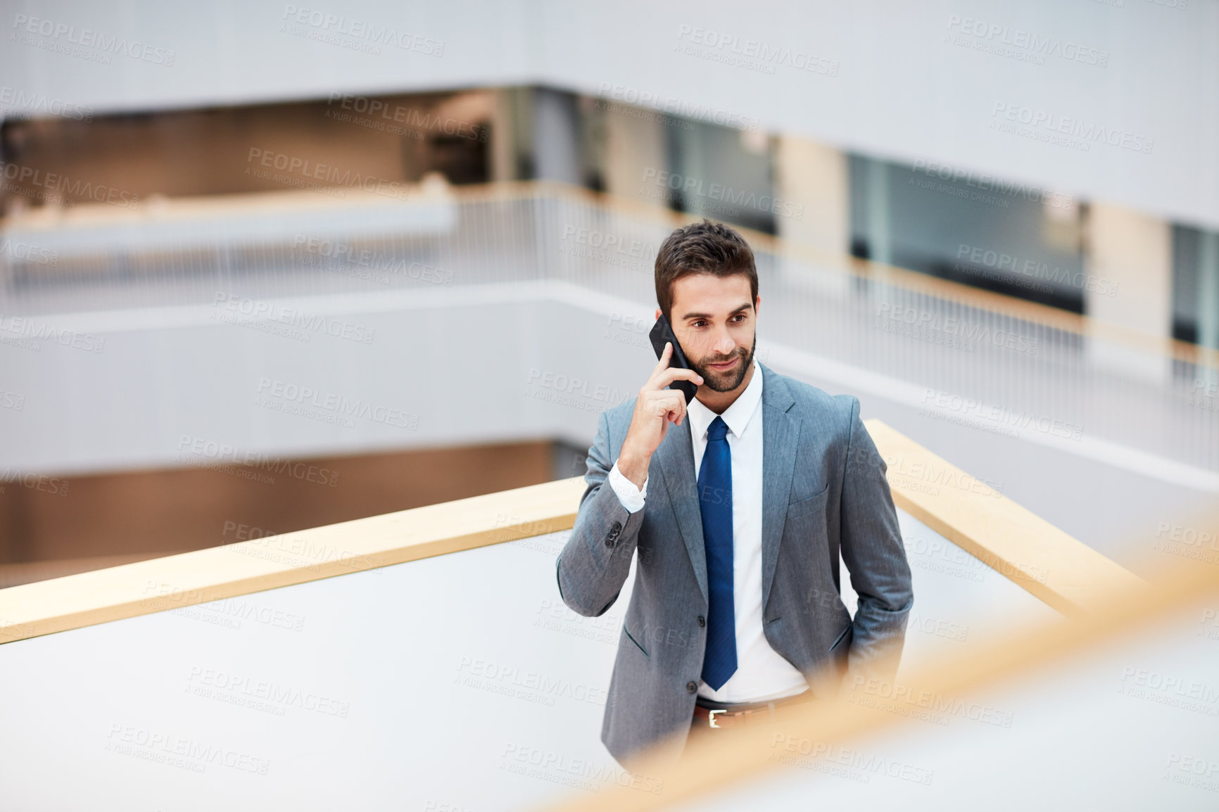 Buy stock photo Shot of a young businessman talking on a cellphone in an office
