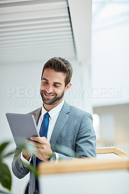 Buy stock photo Shot of a young businessman using a digital tablet in an office