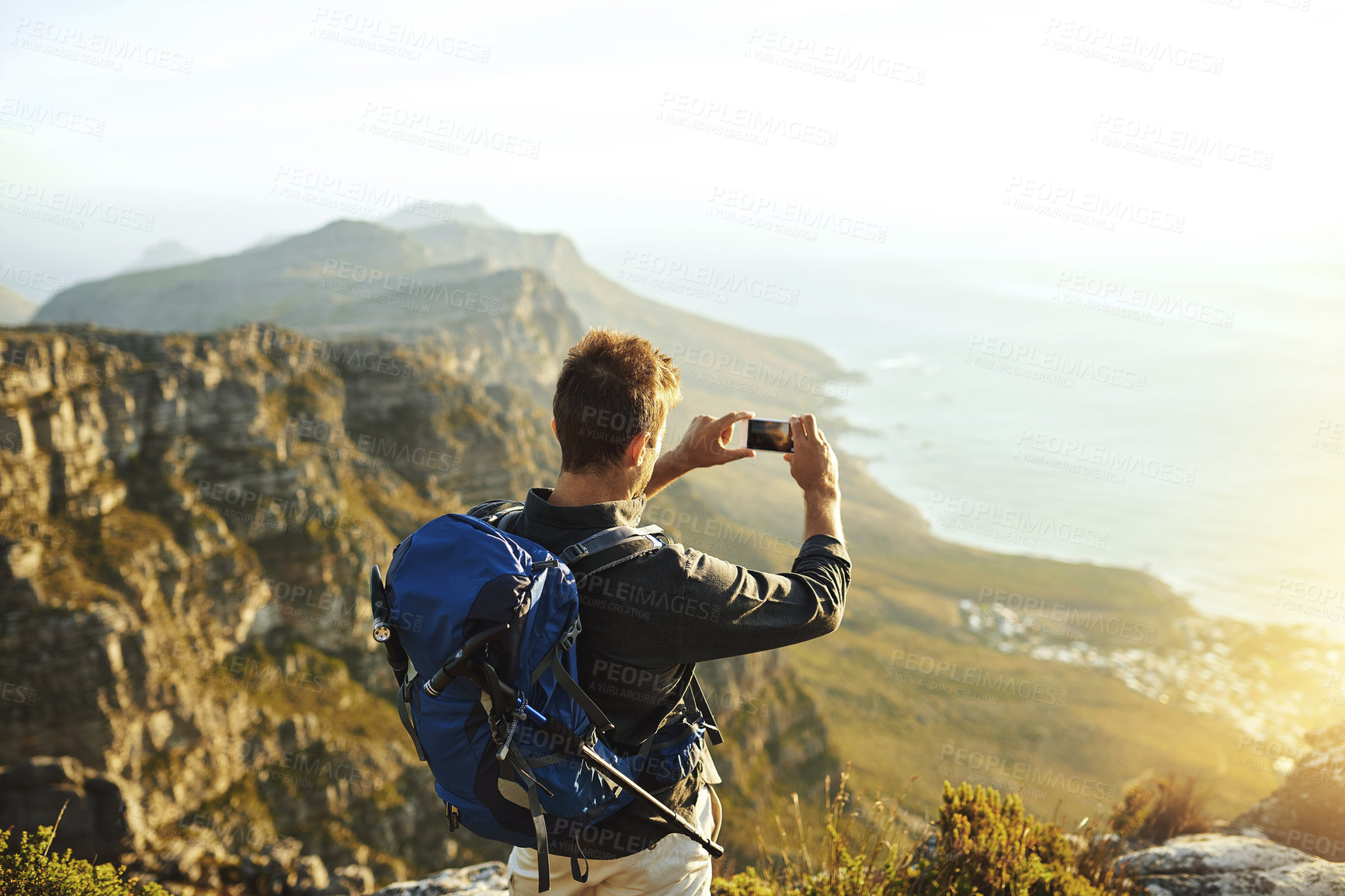 Buy stock photo Photography, hiking and man with phone nature for memory, travel blog or live streaming holiday adventure. Smartphone, view and hiker on mountain cliff with sunset, ocean and outdoor taking picture