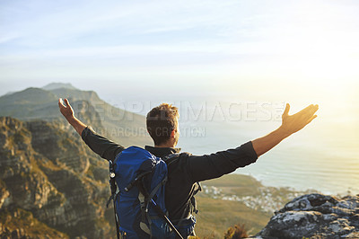 Buy stock photo Shot of a young man cheering while hiking up a mountain