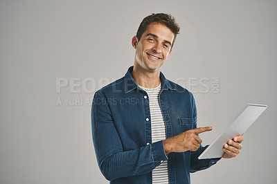 Buy stock photo Pointing, portrait and tablet with man in studio isolated on gray background for app download or update. Smile, social media and website with happy user in casual outfit for online shopping or retail