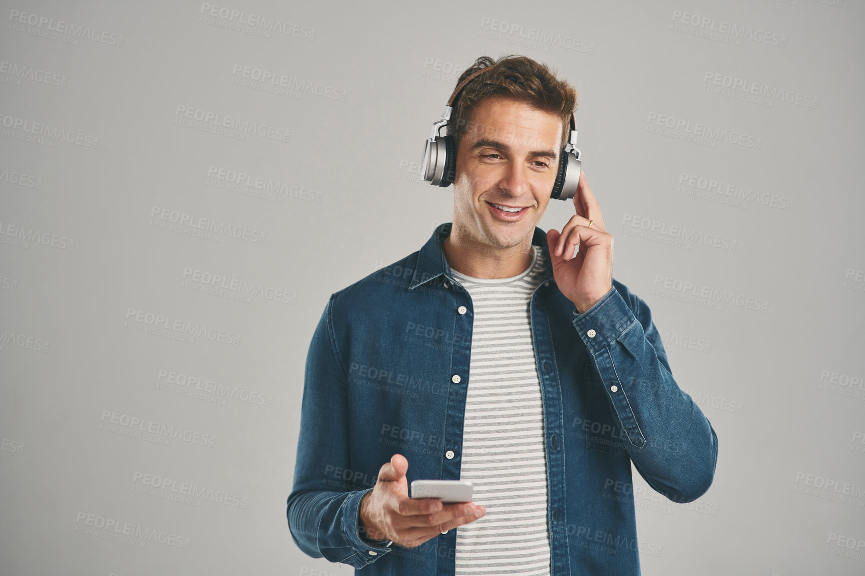 Buy stock photo Man, studio and smartphone on headphones with smile for streaming music, album and playlist on gray background. Male person, mockup space and happy or satisfied on website, online and subscription