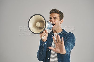 Buy stock photo Studio shot of a young man talking into a megaphone against a grey background