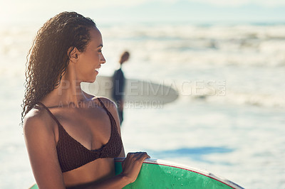 Buy stock photo Shot of a woman at the beach with her surfboard while a male surfer stands in the background