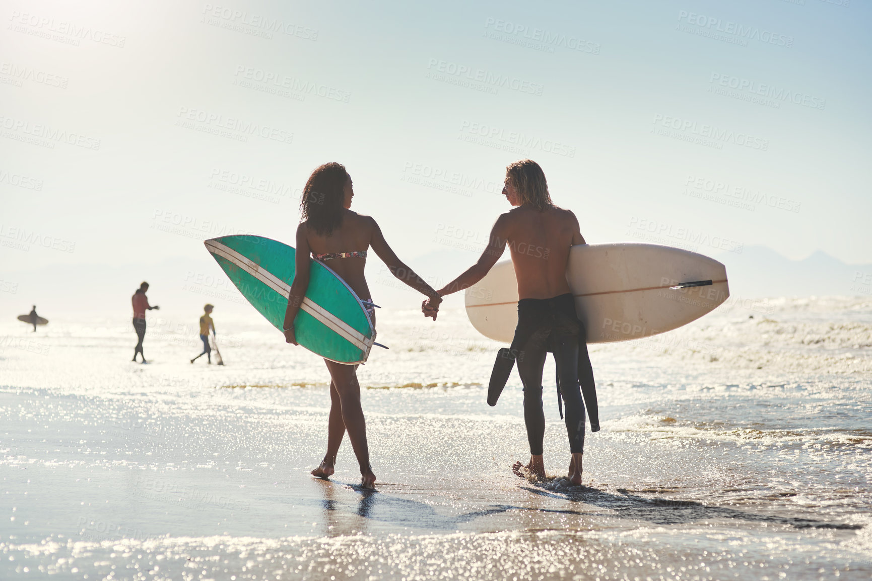 Buy stock photo Shot of a young couple spending the day at the beach with their surfboards