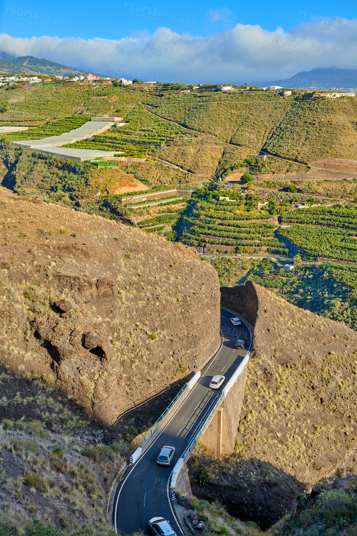 Buy stock photo Beautiful landscape of a countryside tar road with a cloudy blue sky and copy space. Roadway with cars driving to holiday destination close to agriculture farm in Spain on a summer afternoon or day