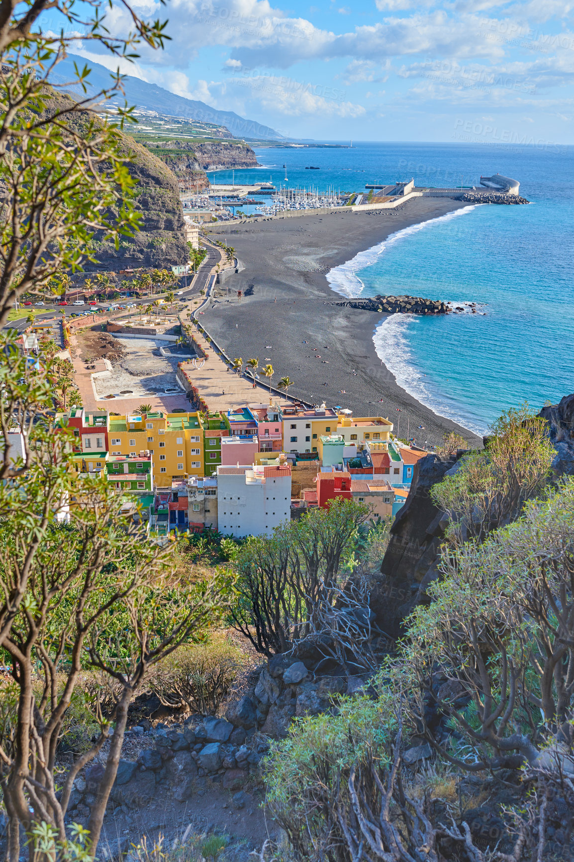 Buy stock photo Landscape of an ocean coast with black beach sand on Puerto de Tazacorte. Colorful town houses or holiday resort accommodation near the seaside in a beautiful tourism destination, La Palma, Spain