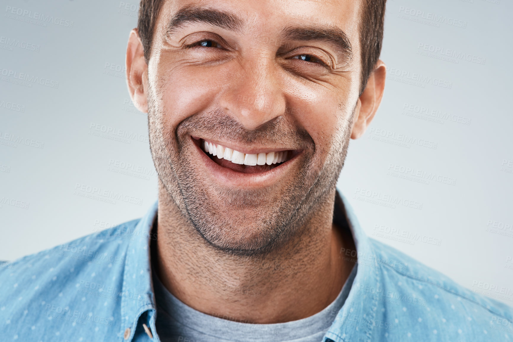 Buy stock photo Portrait of a cheerful young man smiling brightly while standing against a grey background