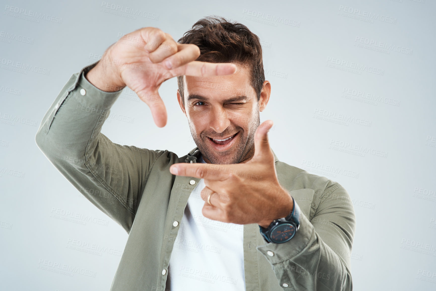 Buy stock photo Portrait of a cheerful young man making frames with his hands to simulate the angle of a camera while standing against a grey background