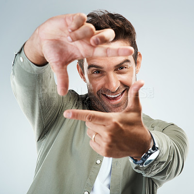 Buy stock photo Hands, frame and portrait of happy man in studio with sign for photo, photography or fun picture. Face, male person and influencer on gray background with finger border, smile for confidence