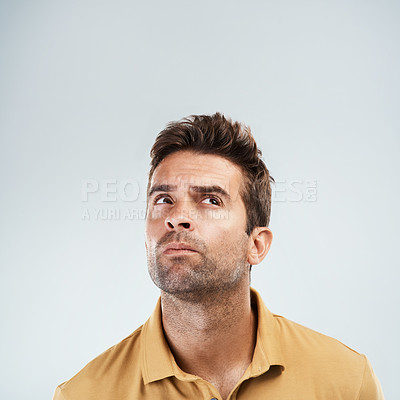 Buy stock photo Studio shot of a young man with a confused facial expression while standing against a grey background