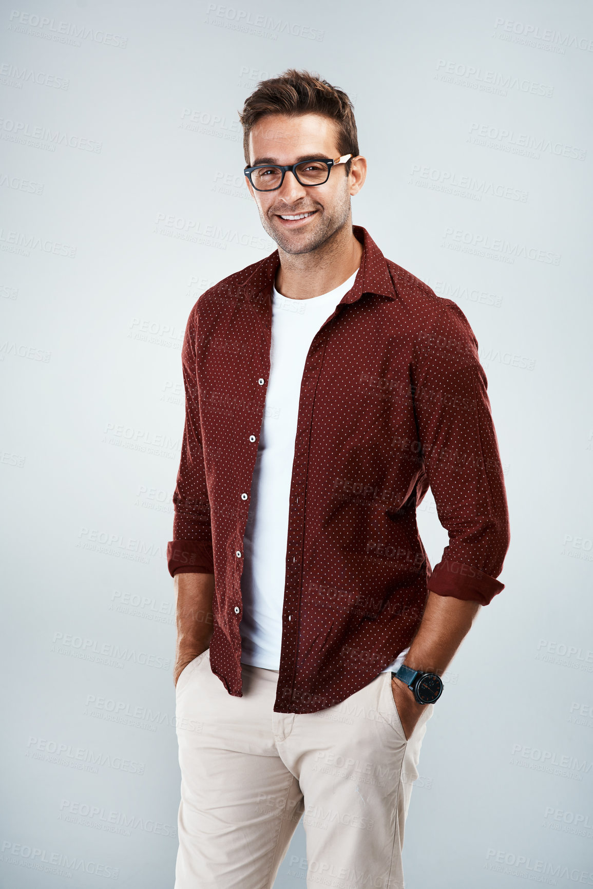 Buy stock photo Portrait of a cheerful young man wearing glasses and smiling brightly while standing against a grey background